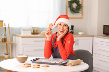 Young woman making tasty gingerbread cookies in kitchen on Christmas eve