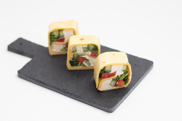 Set of Tortilla sushi rolls with vegetables served on a black slate board