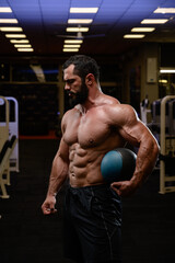 Naklejka na ściany i meble strong caucasian male with beard holding heavy medicine ball in sport fitness gym