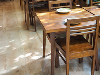 Simple wooden dining table with empty dish and wood chairs.