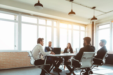 Obraz premium Group of young business people working and communicating while sitting at the office desk together with colleagues sitting. business meeting