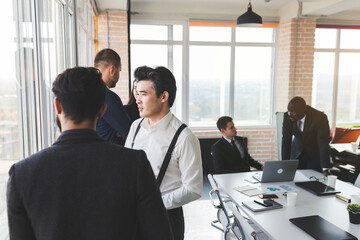 Mature businessman to discuss information with a younger colleague. People working and communicating while sitting at the office desk together with colleagues sitting.