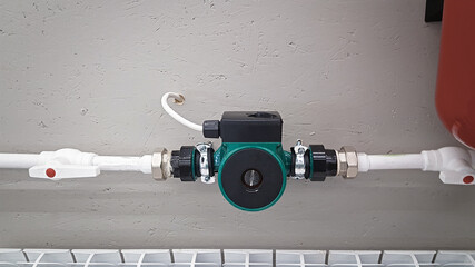 Green heating circulation pump mounted on a pipe. Independent heating system in boiler room at home