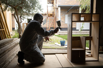 man painting with paint gun furniture, child's kitchen, homemade