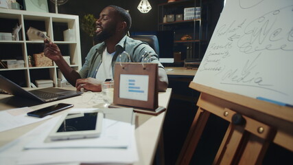 Cheerful african businessman waving dollars bills in office. Afro guy with money