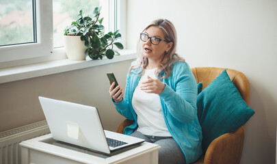 Busy senior woman with blonde hair and glasses is having online meeting o laptop working from home