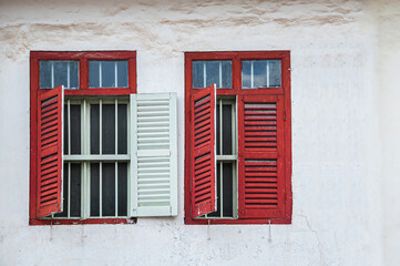 Fototapeta na wymiar Old red window on white concrete wall