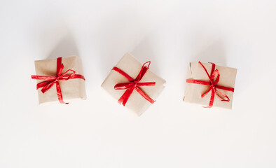 Top view on gift boxes made from craft paper with red ribbon on white background. - 392786527