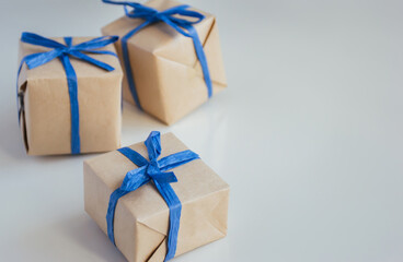 Gift boxes made from craft paper with blue ribbon on white background with copy space.
