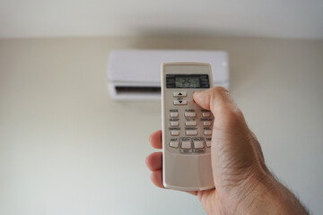 Turn on the air conditioner at 25 degrees Celsius. Hand holding the air conditioner remote control...