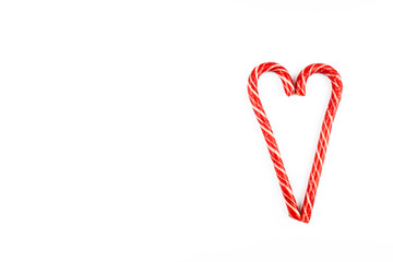 A colorful candy canes in the shapw of the heart lie on a white background