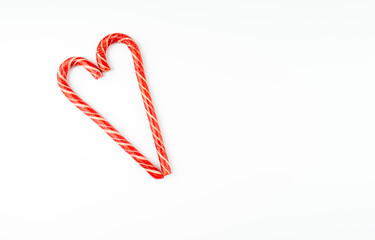Two colorful candy canes in the shape of the heart lie on a white background