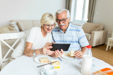 Fototapeta na wymiar Senior couple smiling and looking at the same tablet hugged. Indoor, at home concept. Mature and retired man and woman using technology - lockdown and quarantine lifestyle