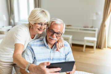 Senior couple taking a selfie with tablet. Elderly couple having a video call with friends or family using tablet