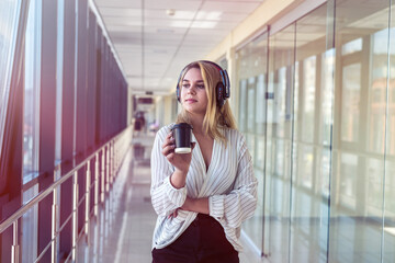 beautiful young woman enjoys coffee and listens to music during lunch break