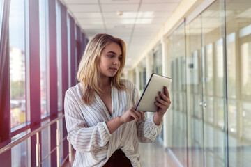 Charm young businesswoman holding digital tablet standing in  corridor of a modern business center