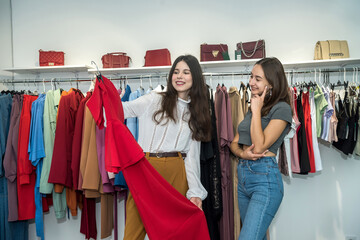 Two beautiful smile friends choosing and shopping at clothing retail store