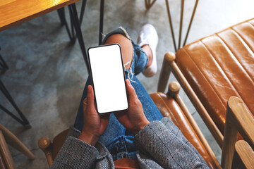 Top view mockup image of a woman holding mobile phone with blank white desktop screen