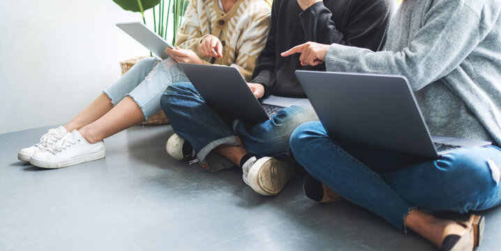 A Group Of Young People Sitting And Using Laptop Computer And Digital Tablet Together