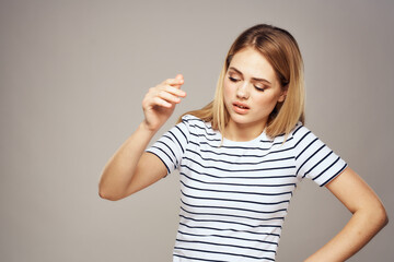 Fototapeta na wymiar A woman with a displeased expression is gesturing with her hands T-shirt gray background