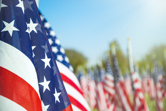 Closeup of an American flag in a row. Blue sky and flags in the background. Copy space. 