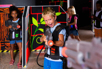 Portrait of teenagers boy with laser gun having fun on dark laser arena