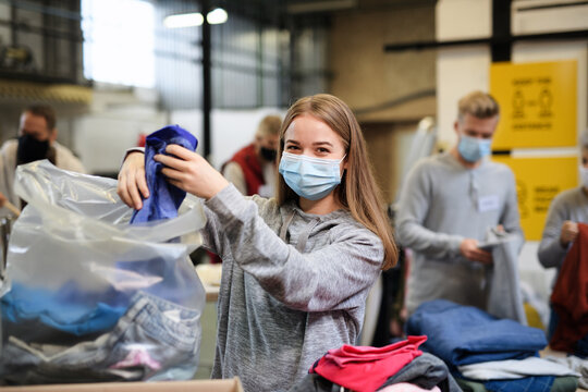 Volunteers sorting out donated clothes in community charity donation center, coronavirus concept.