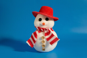 Cute decorative snowman in red hat and scarf on blue background.
