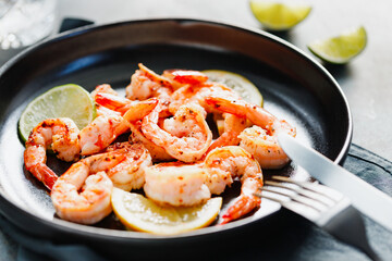 Fried tiger shrimp with lime, lemon and spices on a ceramic dish. Healthy dinner or lunch concept.