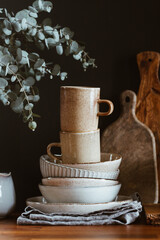 Set of kitchen ceramic tableware and wooden cutting boards on a table. Eco style home still life.