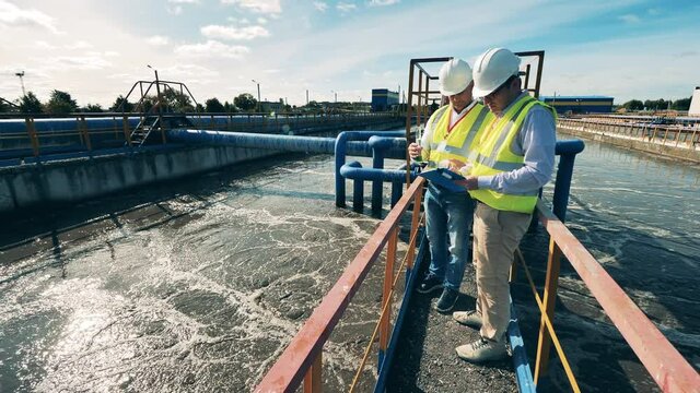 Workers of a sewage cleaning site are analyzing a water probe