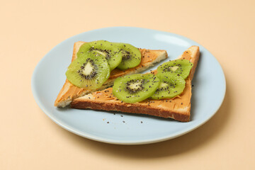 Plate with toasts with kiwi on beige background