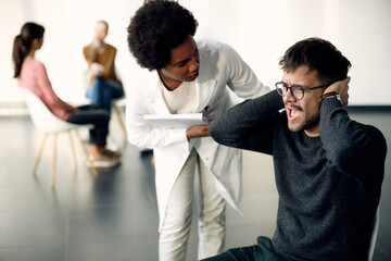 Fototapeta premium Young man screaming while being on group psychotherapy at medical center.
