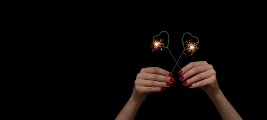 Valentine's Day /Love /Wedding / Birthday / Silvester / New Year / Party background banner - Happy woman holding sparkling heart sparklers in her hands, with red colored nails at black night