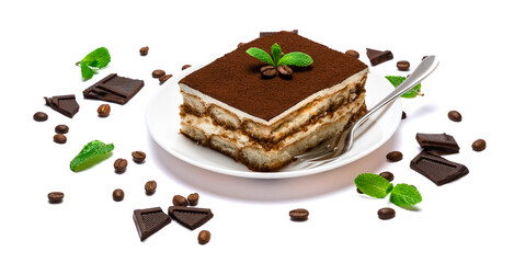 Traditional Italian Tiramisu square dessert portion on ceramic plate, pieces of chocolate bar and coffee beans isolated on white