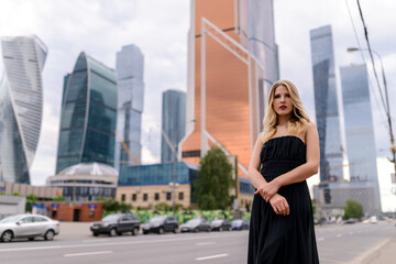 Outdoor portrait of beautiful young woman with skyscrapers on the background.