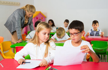 Portrait of children discussing theirs drawings during lesson in school..