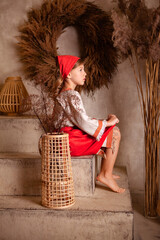 little girl in a light linen shirt and a red scarf in a rustic style