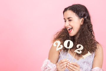 Girl on pink background with wooden numbers 2021