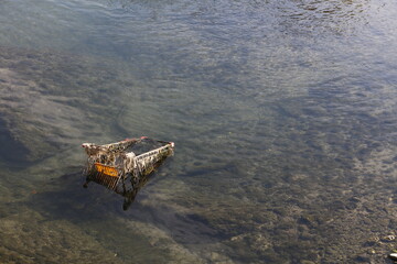 A moody shot of a rusty shopping trolley abandoned on a river, symbolizing economic recession and consumer spending crisis