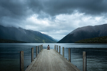 One man sitting on the jetty and watching the storms at Lake Rotoiti, Nelson Lakes National Park.