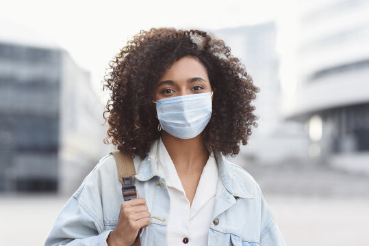 Young woman wearing protective face mask in a city, Masked african student girl on a city street closeup portrait, Epidemic, pandemic, corona virus protection, healthy lifestyle, people concept