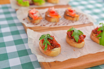 Juicy fresh Italian bruschetta over green plaid table cloth. Traditional Italian cuisine concept.