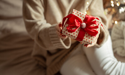 Christmas gift close up in female hands on a blurred background.
