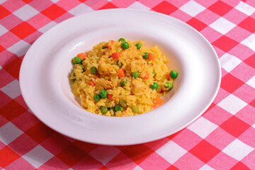 Plain vegetable rice and healthy green vegetables served in a white plate over red plaid background tablecloth.