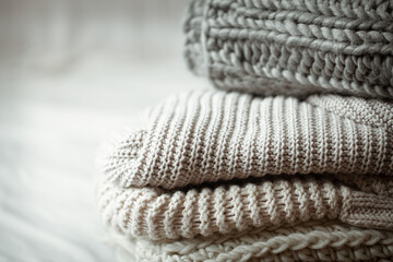 Fototapeta na wymiar A stack of warm knitted items on blurred white background close up.