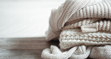 A stack of warm knitted items on blurred white background copy space.