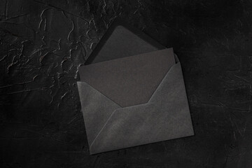 A black card in a black envelope mockup, shot from the top on a black background with a place for...