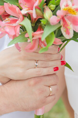 Bride and groom's hand over flower showing the wedding rings.