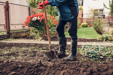 short break from hard manual work with a spade. A man in work clothes and rubber boots is resting. Concept of agriculture life